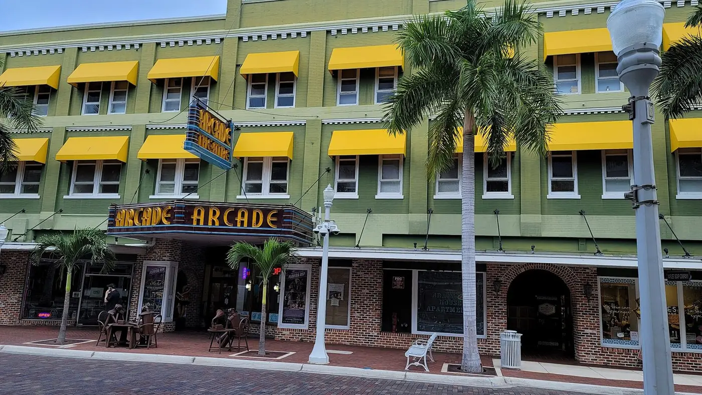 Arcade Theatre with yellow awnings and palm trees on a downtown Fort Myers street